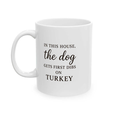 White Thanksgiving mug with humorous black text saying "In this house, the dog gets first dibs on turkey"
